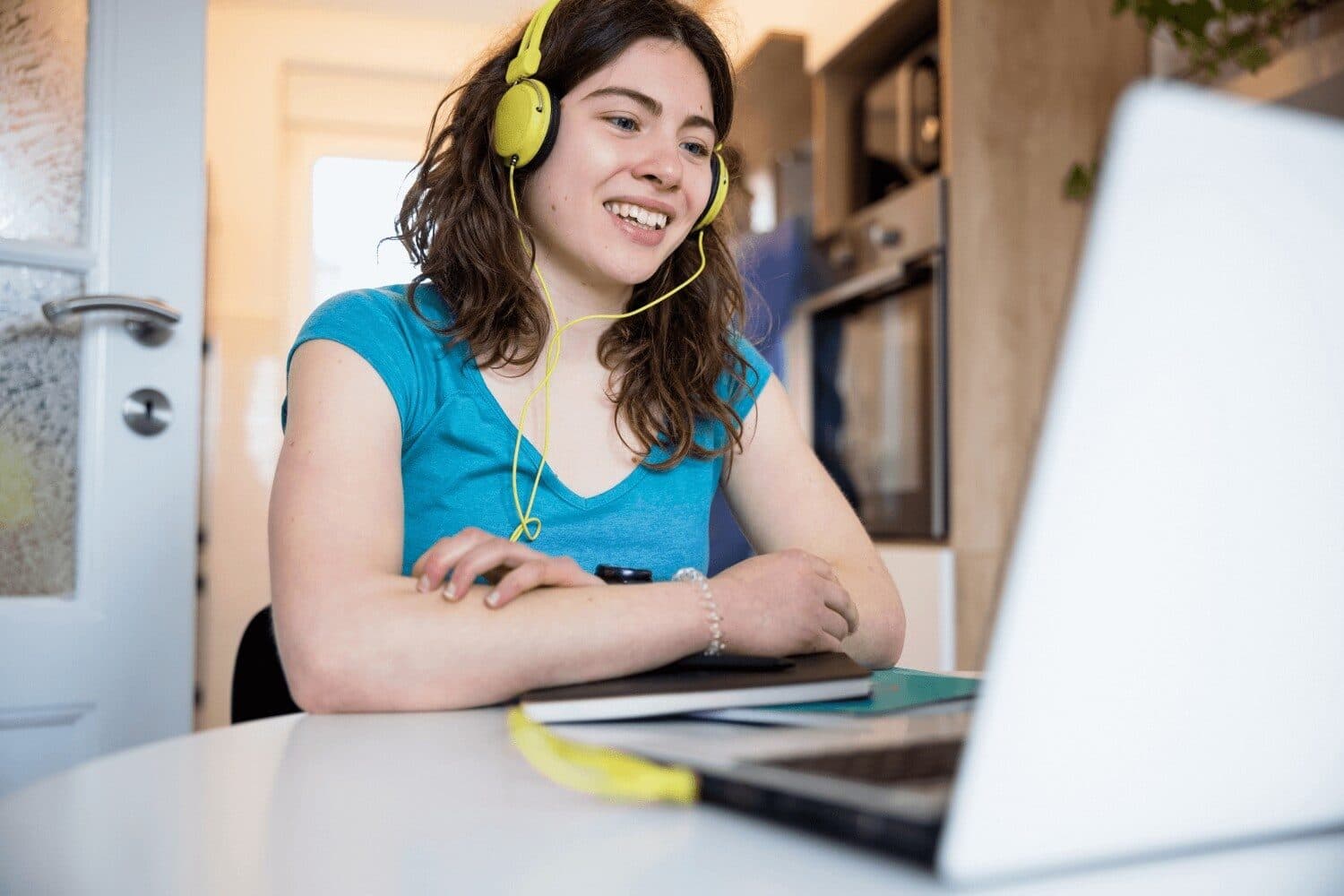 A young person at a laptop wearing headphones during an online session